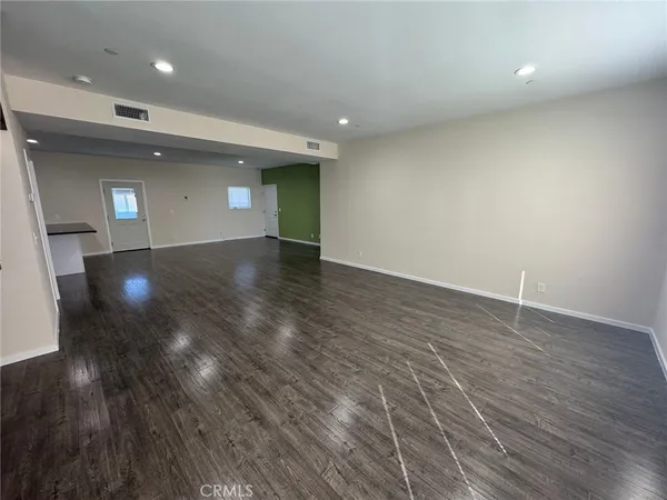 an empty room with wooden floor and entrance