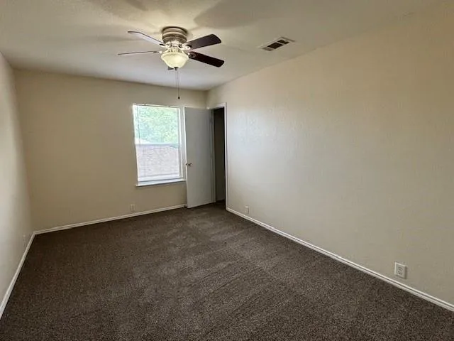 an empty room with a window and a fan