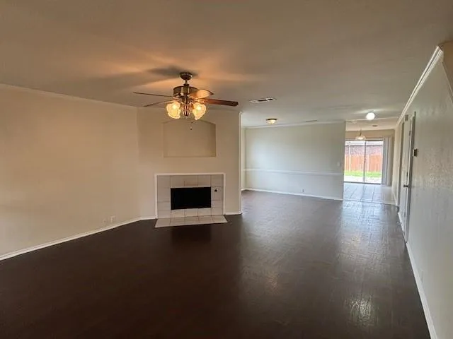 an empty room with wooden floor fireplace and windows
