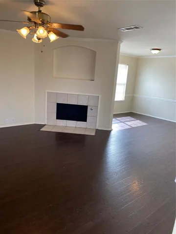 a view of an empty room with wooden floor fireplace and a window