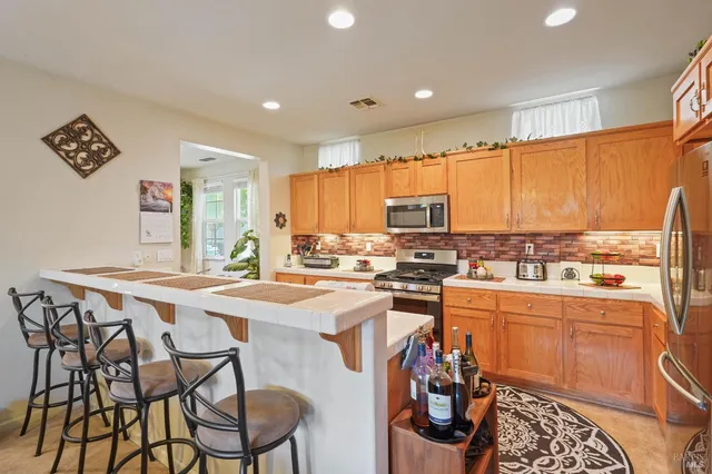 a kitchen with a stove a sink dishwasher and a refrigerator with wooden table