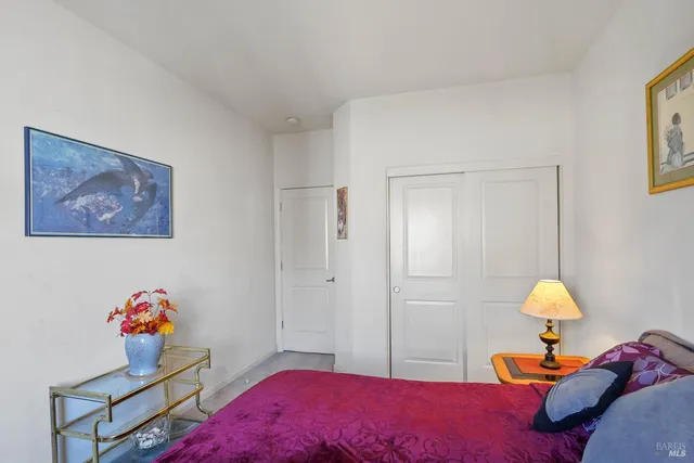 a bedroom with a bed and dresser with wooden floor