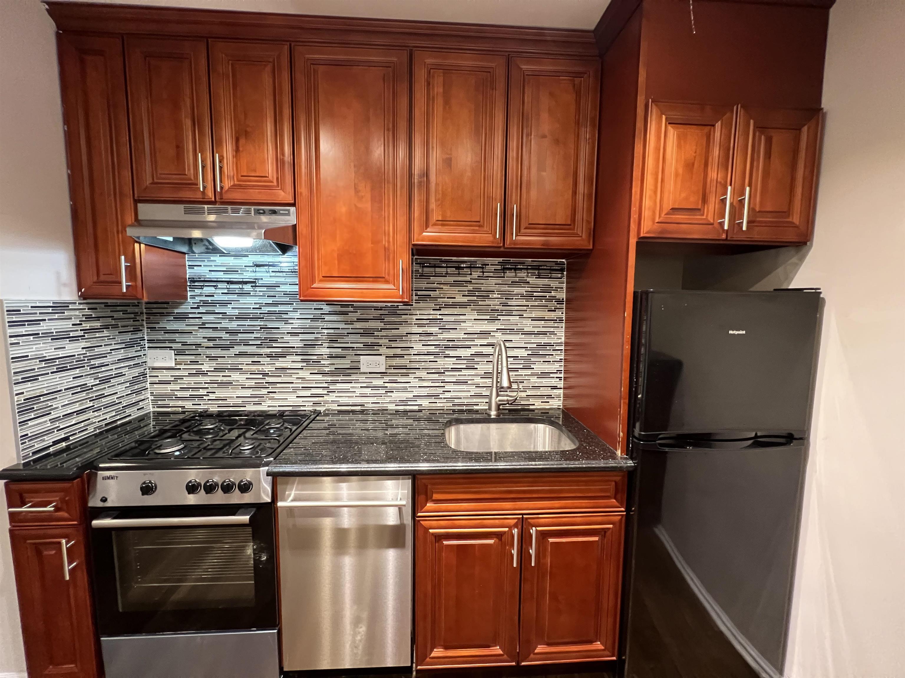 8550 Boulevard East, Unit 3C North Bergen, NJ 07047 - Photo 11 of 25 a kitchen with granite countertop wooden cabinets and a stove top oven