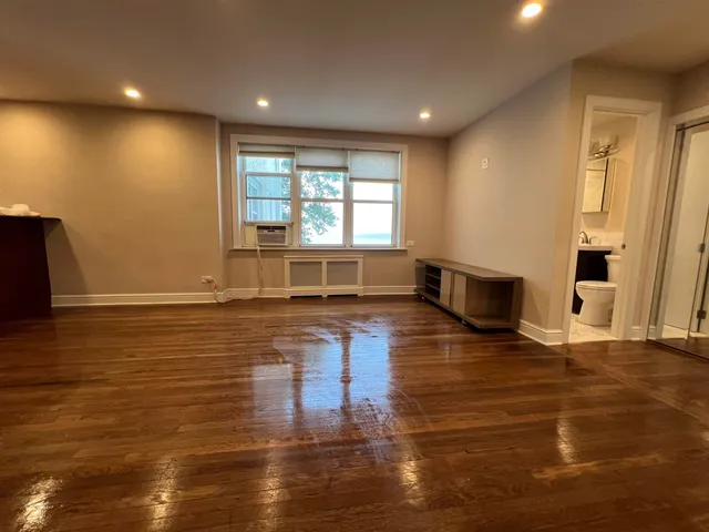 an empty room with wooden floor and stainless steel appliances