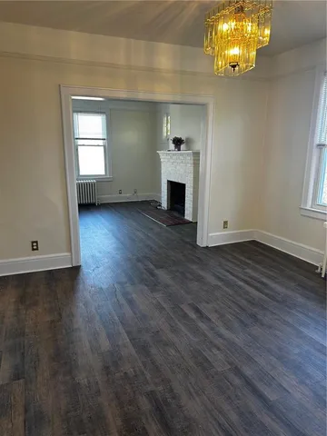 an empty room with wooden floor a fireplace and windows