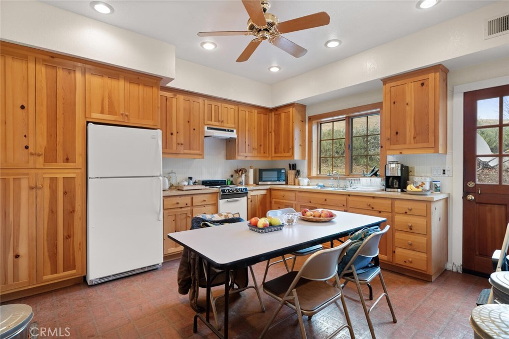 3576 Dry Creek Road Oroville, CA 95965 - Photo 45 of 75 a kitchen with a refrigerator a stove a sink a dining table and chairs