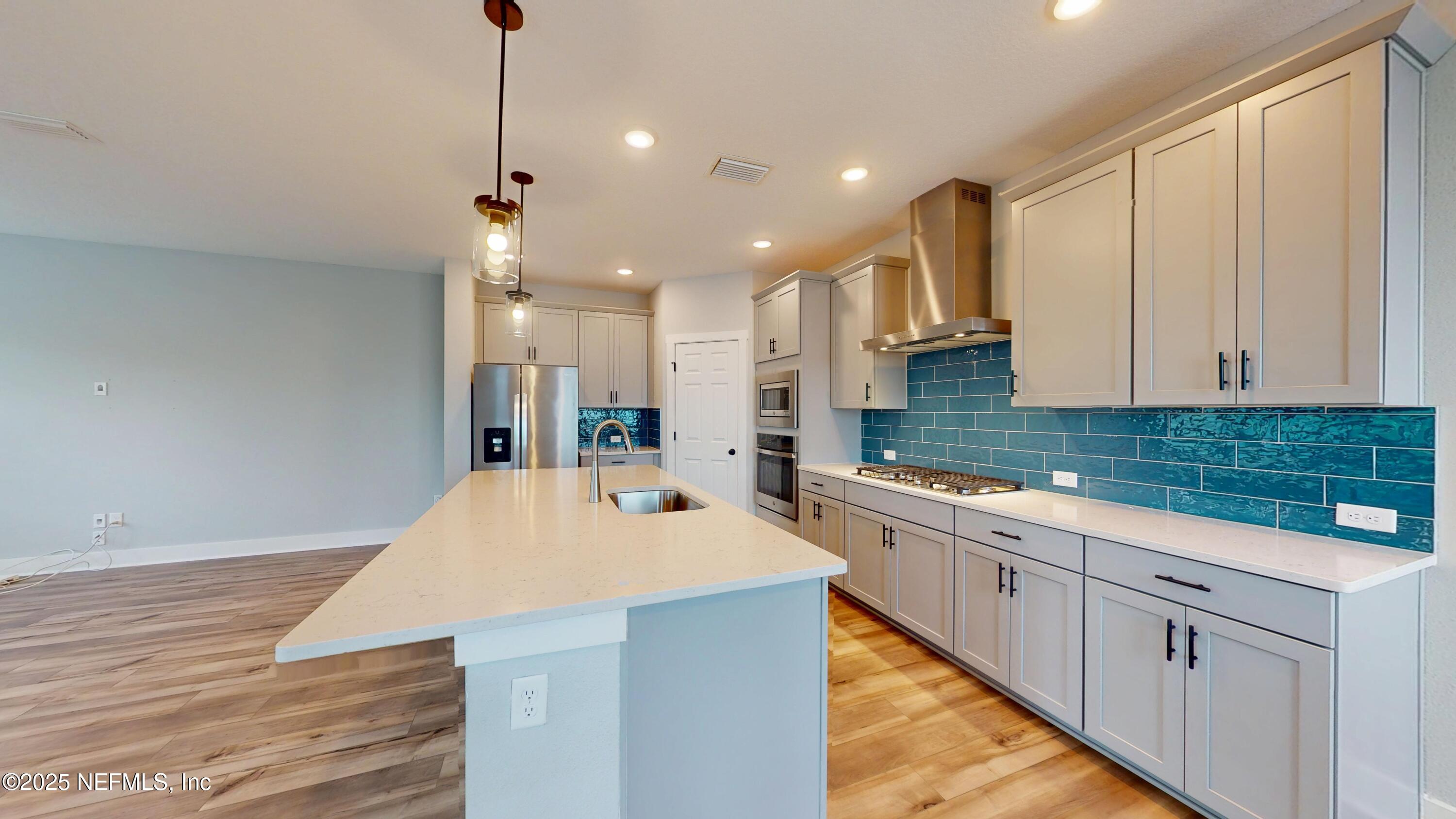 9921 Element Road Jacksonville, FL 32256 - Photo 7 of 37 a kitchen with stainless steel appliances kitchen island granite countertop a sink and white cabinets with wooden floor