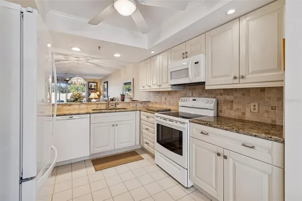 a kitchen with stainless steel appliances kitchen island granite countertop a stove a sink dishwasher and white cabinets with wooden floor
