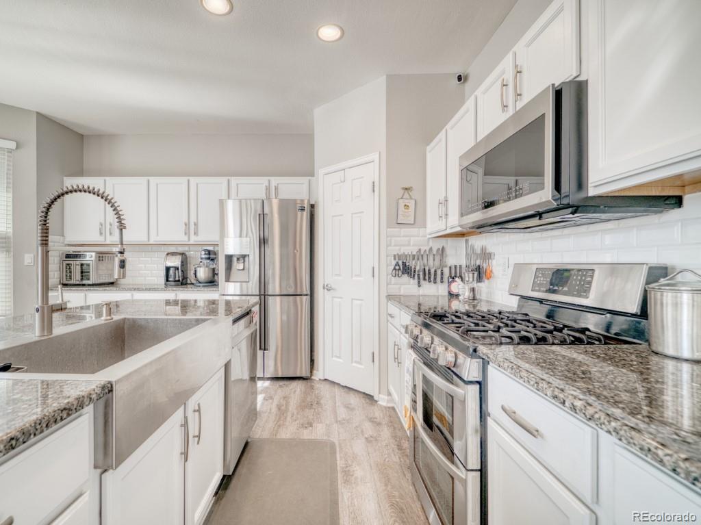 1864 Mountain Maple Avenue Highlands Ranch, CO 80129 - Photo 4 of 35 a kitchen with stainless steel appliances granite countertop a sink stove a refrigerator and cabinets