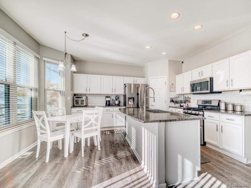 1864 Mountain Maple Avenue Highlands Ranch, CO 80129 - Photo 6 of 35 a kitchen with stainless steel appliances a stove a sink a refrigerator white cabinets and chairs