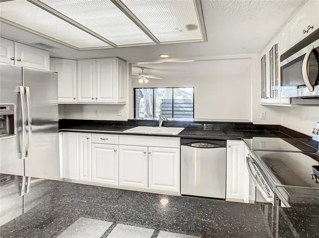a kitchen with stainless steel appliances granite countertop a sink a stove a microwave a counter space and cabinets