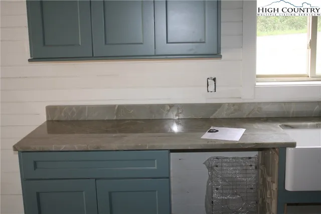 a view of kitchen with granite countertop white cabinets and a sink