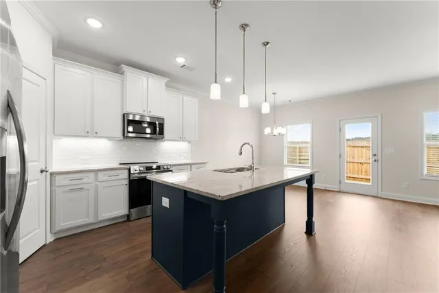 a kitchen with stainless steel appliances granite countertop a sink a stove and a wooden floors