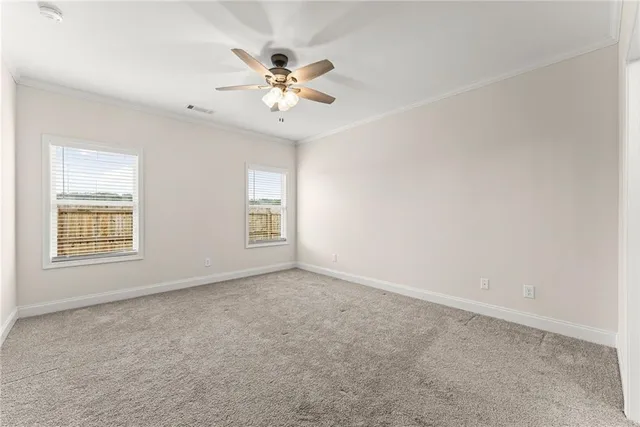 an empty room with windows and chandelier fan