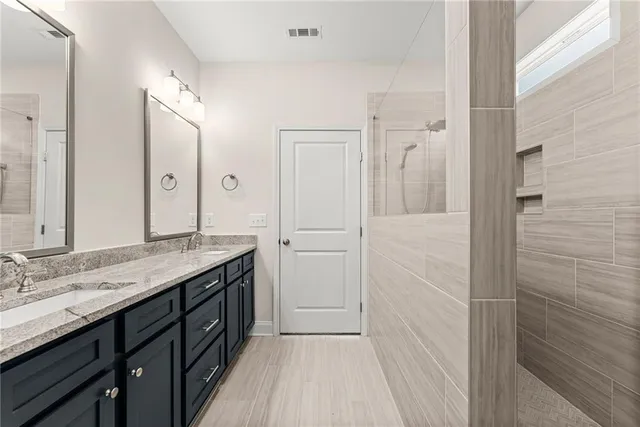 a spacious bathroom with a granite countertop sink a mirror and a shower