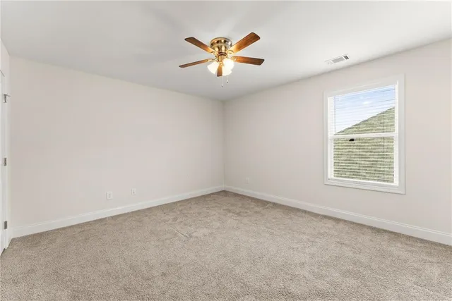 an empty room with ceiling fan and window