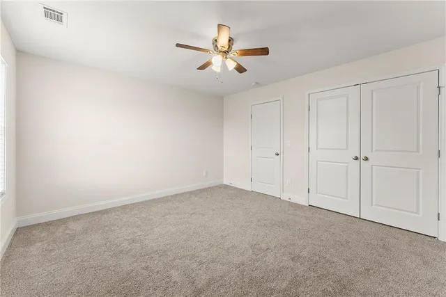 an empty room with closet and fan