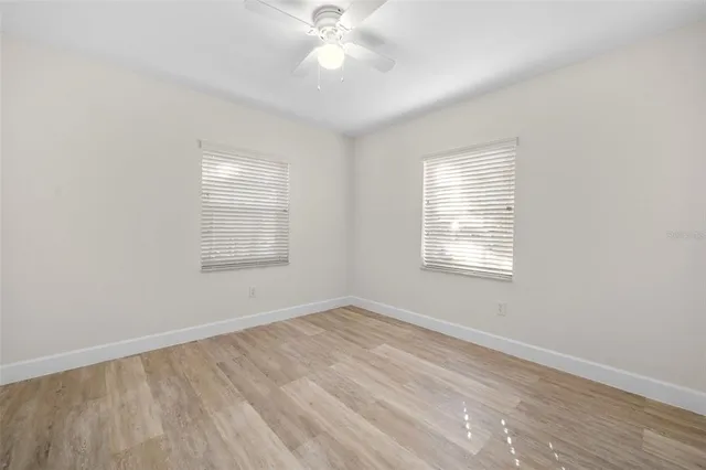 an empty room with windows and fan