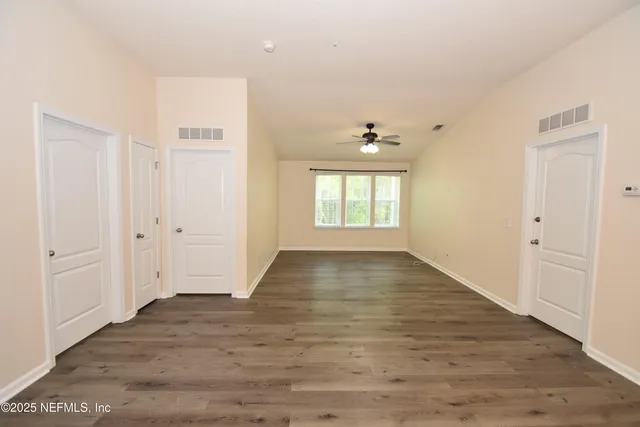an empty room with wooden floor and windows