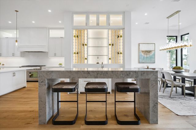 a kitchen with granite countertop a table chairs wooden floors and a view of living room