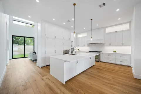 a large kitchen with stainless steel appliances a large counter top and a wooden floors
