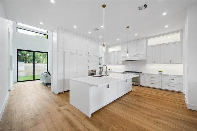 a large kitchen with stainless steel appliances a large counter top and a wooden floors