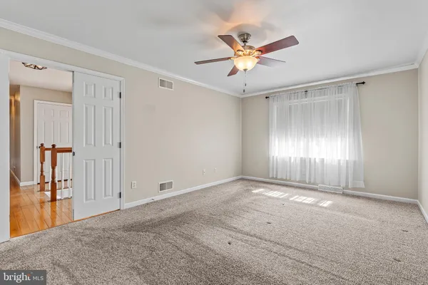 an empty room with chandelier fan and closet area