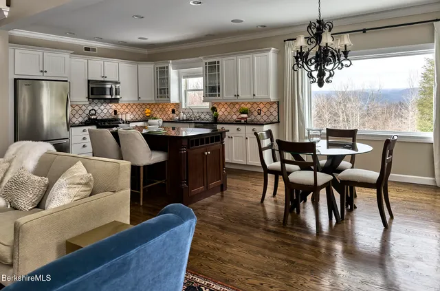 a kitchen with stainless steel appliances granite countertop a stove a refrigerator a kitchen island a dining table and chairs