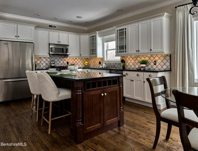 a kitchen with stainless steel appliances granite countertop a table chairs microwave and sink
