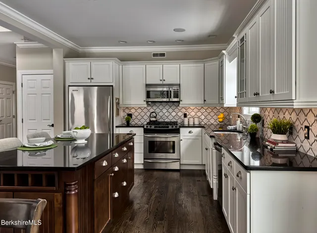 a kitchen with granite countertop stainless steel appliances a stove a sink a refrigerator and cabinets