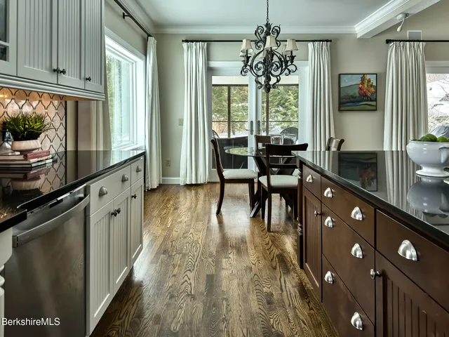 a kitchen with stainless steel appliances granite countertop a stove top oven a sink dishwasher a dining table and chairs with wooden floor