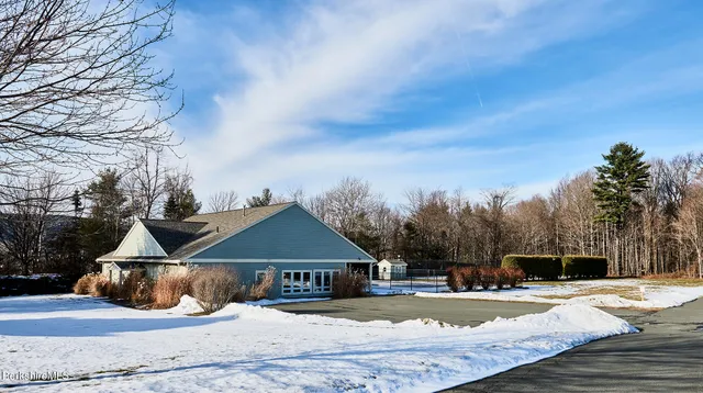 a front view of a house with yard and trees in the background