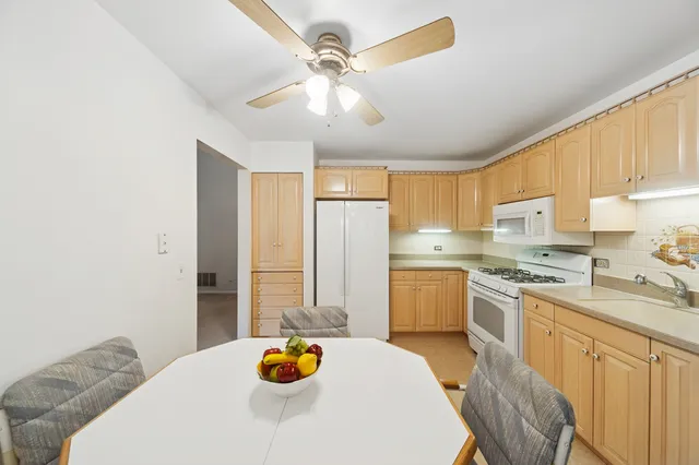 a kitchen with a sink dishwasher a stove a refrigerator and a dining table with wooden floor