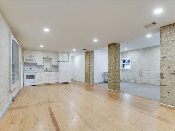 a view of a kitchen with kitchen island wooden floor wooden cabinets and stainless steel appliances