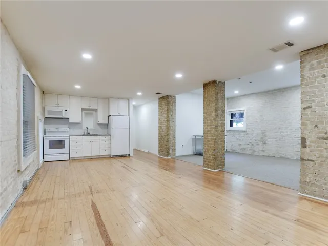 a view of a kitchen with kitchen island wooden floor wooden cabinets and stainless steel appliances