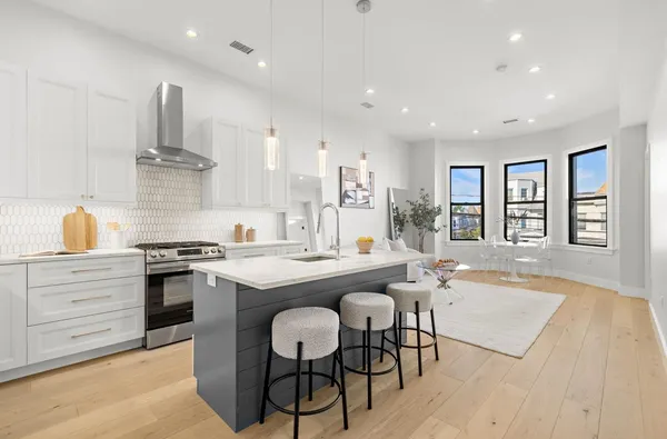 a kitchen with stainless steel appliances granite countertop a stove top oven a sink a dining table and chairs with wooden floor