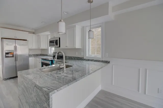 a kitchen with stainless steel appliances granite countertop a sink a stove and a refrigerator