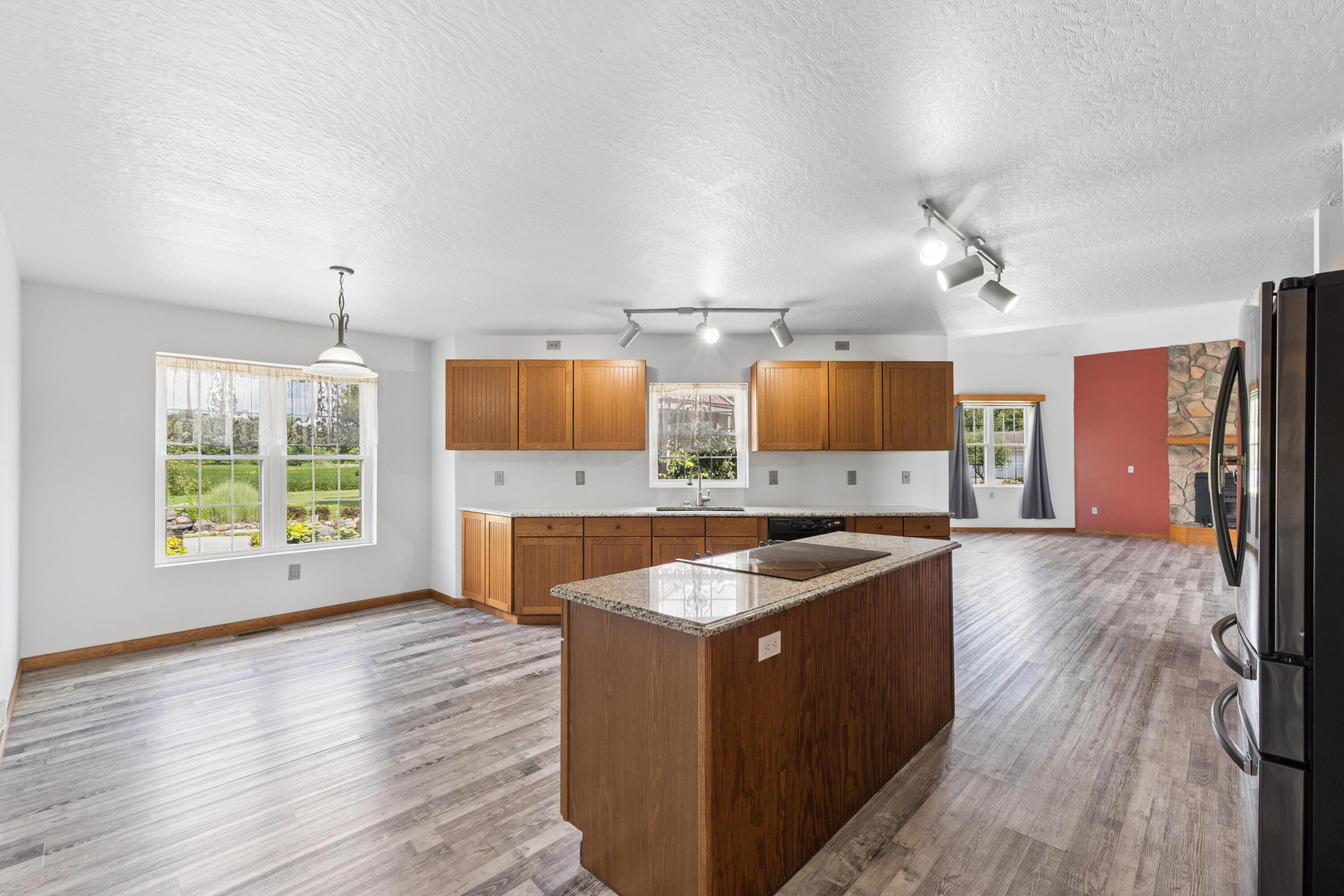 18964 London Road Circleville, OH 43113 - Photo 27 of 57 Kitchen featuring wood cabinetry, a center island with a cooktop and stone countertop, and wood-finish flooring