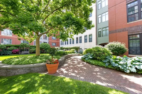 a front view of a building with a yard and trees