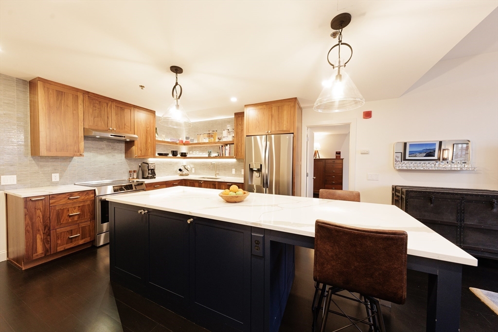 29 Otis Street, Unit 407 Cambridge, MA 02141 - Photo 8 of 31 a large kitchen with a table chairs refrigerator and cabinets