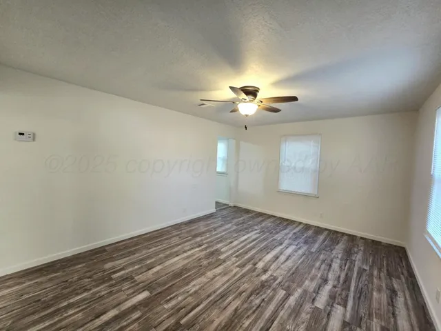 wooden floor in an empty room with a chandelier fan
