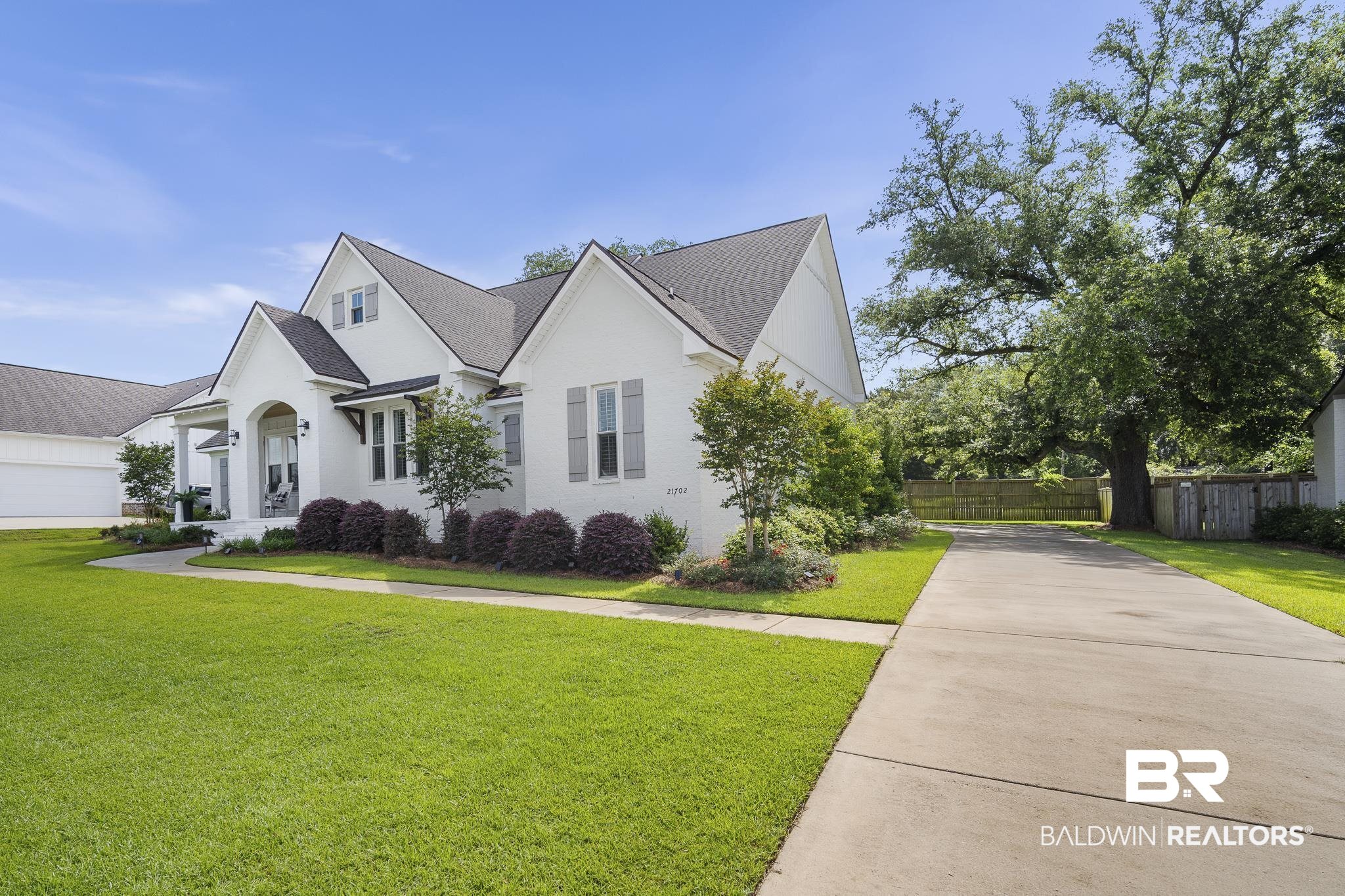 21702 Pillars Street Fairhope, AL 36532 - Photo 41 of 54 White brick home with a covered front porch, grey shutters, and a dark shingle roof
