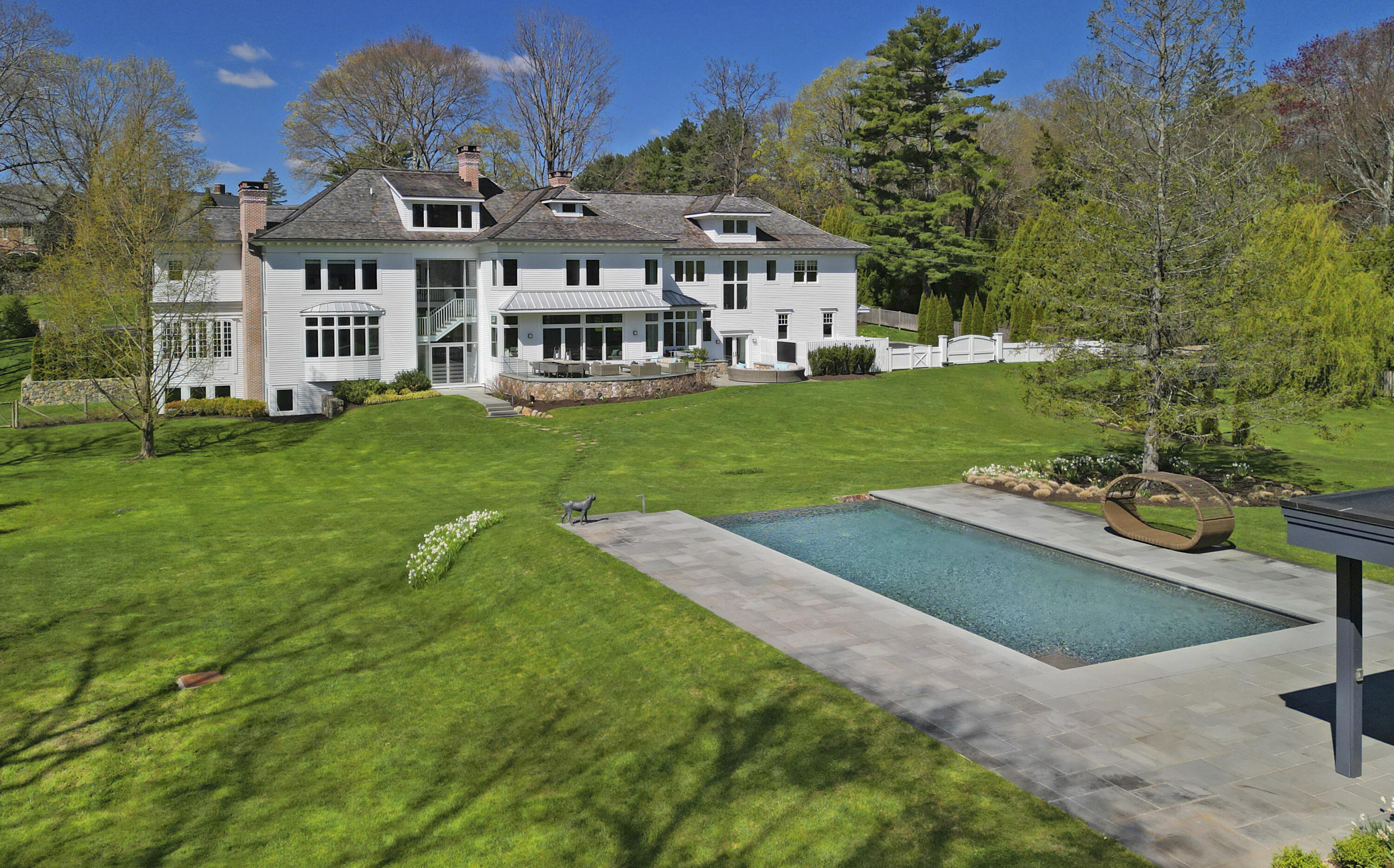 549 Oenoke Ridge New Canaan, CT 06840 - Photo 42 of 54 a front view of a house with a yard table and chairs