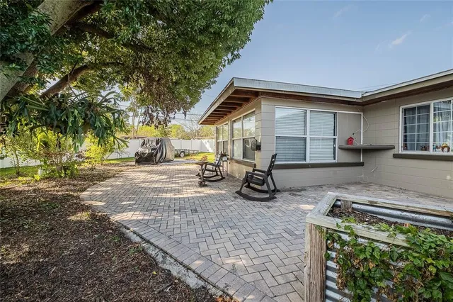 a view of a house with large trees and playing area