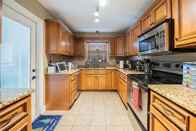 a large kitchen with stainless steel appliances granite countertop a stove top oven a sink dishwasher a dining table and chairs with wooden floor