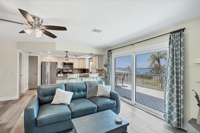 a kitchen with stainless steel appliances kitchen island granite countertop a refrigerator a stove a sink and white cabinets with wooden floor