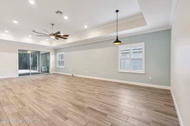 a view of an empty room with a window and wooden floor