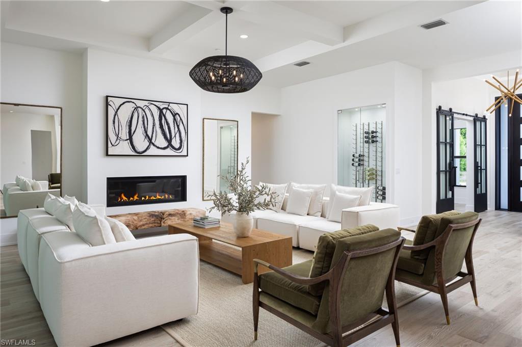 5772 Green Boulevard Naples, FL 34116 - Photo 8 of 24 a living room with furniture a fireplace and a chandelier