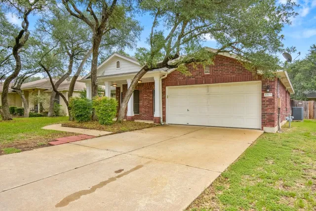 a front view of a house with a garden and trees