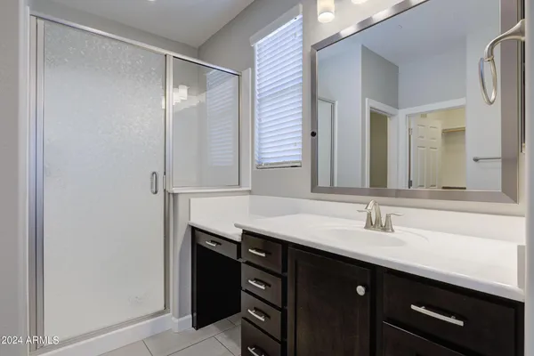 a bathroom with a granite countertop sink a mirror and a shower